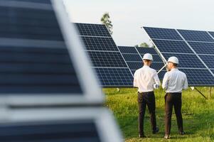 le solaire ferme solaire panneau avec deux ingénieurs marcher à vérifier le opération de le système, alternative énergie à conserver le du monde énergie, photovoltaïque module idée pour nettoyer énergie production. photo