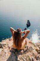 femme Voyage mer. content touristique prendre plaisir prise image en plein air pour souvenirs. femme voyageur regards à le bord de le falaise sur le mer baie de montagnes, partage Voyage aventure périple photo