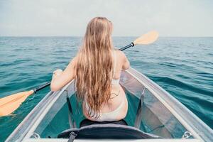 femme dans kayak retour voir. content Jeune femme avec longue cheveux flottant dans transparent kayak sur le cristal clair mer. été vacances vacances et de bonne humeur femelle gens relaxant ayant amusement sur le bateau photo