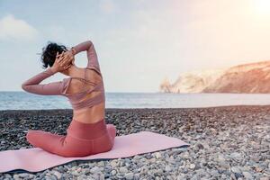 femme mer pilates. sportif content milieu vieilli femme pratiquant aptitude sur plage près mer, souriant actif femelle formation avec bague sur yoga tapis dehors, profiter en bonne santé mode de vie, harmonie et méditation photo