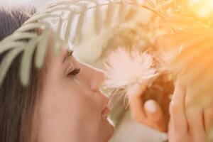 beauté portrait de content femme fermer. Jeune fille odeur chinois acacia rose épanouissement fleurs. portrait de Jeune femme dans épanouissement printemps, été jardin. romantique ambiance. femelle et la nature photo