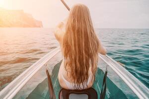 femme dans kayak retour voir. content Jeune femme avec longue cheveux flottant dans transparent kayak sur le cristal clair mer. été vacances vacances et de bonne humeur femelle gens relaxant ayant amusement sur le bateau photo