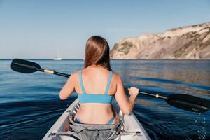 femme dans kayak retour voir. content Jeune femme avec longue cheveux flottant dans kayak sur calme mer. été vacances vacances et de bonne humeur femelle gens relaxant ayant amusement sur le bateau. photo