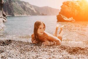 femme Voyage mer. content touristique dans chapeau prendre plaisir prise image en plein air pour souvenirs. femme voyageur posant sur le plage à mer entouré par volcanique montagnes, partage Voyage aventure périple photo