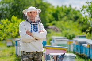 portrait de Masculin apiculteur avec urticaire à Contexte. protecteur vêtements sur. rucher. photo