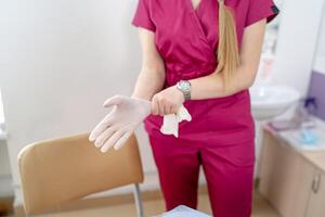femme médecin portant médical stérile gants. sélectif concentrer sur mains. moderne clinique intérieur dans le Contexte. photo