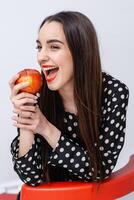 Pomme dans fille mains. souriant fille mordant un Pomme. blanc arrière-plan. photo