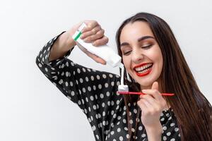 Jeune femme en portant une brosse à dents et placement dentifrice sur il. dentaire se soucier concept. photo