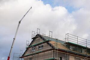 réparation de le toit de une Résidentiel bâtiment. échafaudage et construction grue. photo