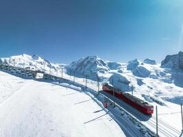 aérien vue de une rouge train dans le neigeux Zermatt ski station balnéaire, Suisse Alpes. photo