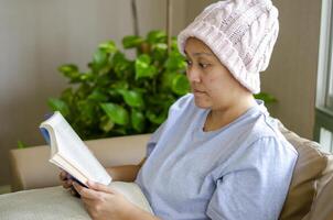 asiatique femme avec cancer est assis avec une livre à soulager stress. photo