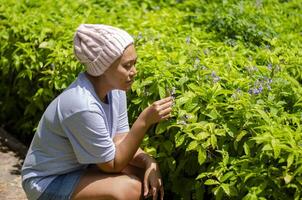 asiatique femme avec cancer, elle se sent rafraîchi et content à aller pour une marcher et Regardez à fleurs dans le jardin. photo