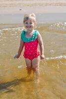 Jeune content enfant fille de européen apparence âge de 4 ayant amusement dans l'eau sur le plage ,tropical été vocations,vacances.a enfant jouit le mer.vertical photo. photo