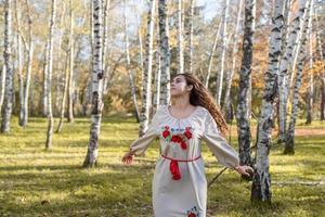 Belle femme en vêtements de costume traditionnel national ukrainien dansant en forêt photo