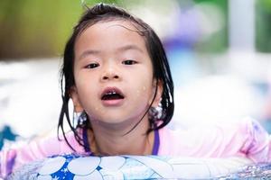 coup de tête d'une jolie fille asiatique nageant avec un anneau en caoutchouc. heure d'été. fille sportive. enfant d'exercice. enfant actif de 4 à 5 ans. photo