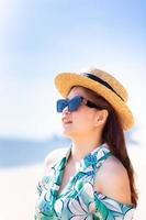 image verticale. belles femmes asiatiques avec mer et ciel en été. femme porte des lunettes de soleil et un chapeau de paille. portrait fille heureuse. la mode avec les voyages.