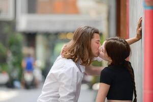 une couple est profiter une été vacances dans le communauté des rues, Heureusement montrant leur l'amour à chaque autre. photo