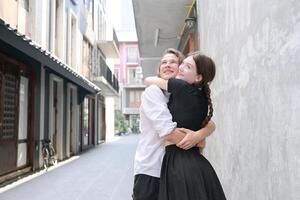 une couple est profiter une été vacances dans le communauté des rues, Heureusement montrant leur l'amour à chaque autre. photo
