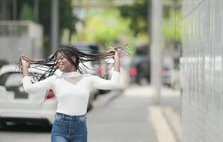 une Jeune femme avec le sien coiffure et le atmosphère de vivant dans le communauté. photo