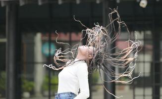 une Jeune femme avec le sien coiffure et le atmosphère de vivant dans le communauté. photo