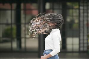 une Jeune femme avec le sien coiffure et le atmosphère de vivant dans le communauté. photo