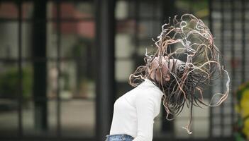 une Jeune femme avec le sien coiffure et le atmosphère de vivant dans le communauté. photo