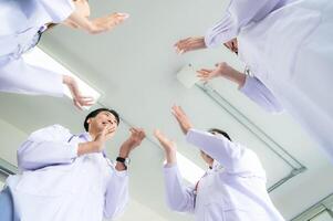 une Enchanté médecin équipe profiter réussite dans une hôpital réglage avec taper mains. photo