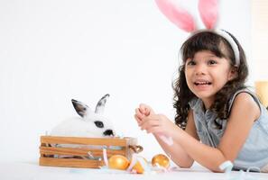 souriant peu fille et avec leur bien-aimée duveteux lapin, mettant en valeur le beauté de relation amicale entre humains et animaux photo