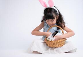 souriant peu fille et avec leur bien-aimée duveteux lapin, mettant en valeur le beauté de relation amicale entre humains et animaux photo