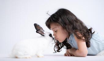 une peu fille baisers sa bien-aimée duveteux lapin, le beauté de relation amicale entre humains et animaux photo