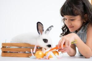 souriant peu fille et avec leur bien-aimée duveteux lapin, mettant en valeur le beauté de relation amicale entre humains et animaux photo