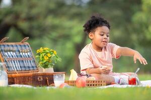 content famille profiter une pique-nique dans le parc, avec enfant en mangeant confiture pain, entouré par la nature photo