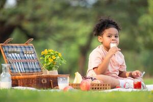 content famille profiter une pique-nique dans le parc, avec enfant en mangeant confiture pain, entouré par la nature photo