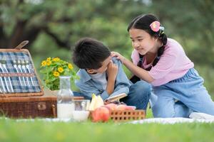 content famille profiter une pique-nique dans le parc, les enfants séance et en train de lire livres. photo
