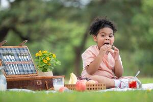 content famille profiter une pique-nique dans le parc, avec enfant en mangeant confiture pain, entouré par la nature photo