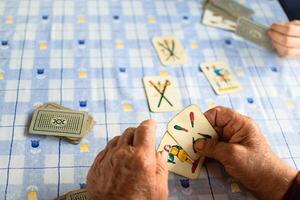 aîné mains en jouant cartes sur une bleu table photo