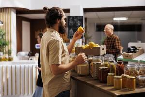 homme dans zéro déchets boutique en cours d'analyse citrons, fabrication Bien sur elles ou ils sont ferme grandi et fraîchement récolté. en bonne santé vivant client complètement vérification local supermarché nourriture articles sont pesticides gratuit photo