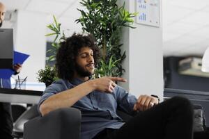 ponctuelle arabe début en haut entreprise directeur vérification temps sur montre-bracelet dans affaires bureau. souriant Jeune homme d'affaire à la recherche à regarder sur main, montrant entreprise productivité concept photo