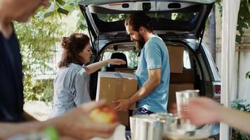 à nourriture conduire, Masculin bénévole donne don des boites de le voiture à le nécessiteux et Moins privilégié personnes. groupe de bénévoles distribuer nécessités à le pauvres et sans abri personnes. trépied tir. photo