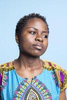 portrait de charmant la personne portant traditionnel étranger tenue, sur de soi femme sur caméra. africain américain fille cette rayonne élégance et est une Naturel beauté, sérieux expression. photo