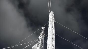 couvert de neige radio la tour sur Contexte ciel. agrafe. congelé structure de électrique la tour dans l'hiver. radio tours couvert avec neige sur ensoleillé hiver journée photo