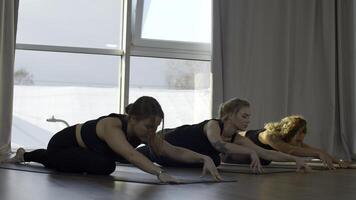 femmes pendant groupe formation dans yoga des sports centre. médias. Jeune femelle les athlètes élongation muscles sur tapis. photo