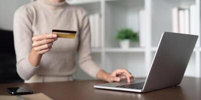 Jeune femme en portant crédit carte en utilisant portable Paiement à maison. femelle client achats fabrication achat en ligne sur portable photo