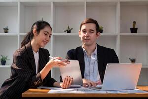 équipe affaires de diverse les partenaires affaires femme discuter projet sur portable et tablette dans bureau. deux collègues de professionnel affaires gens travail ensemble photo