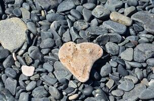 Naturel cœur en forme de dégringolé pierre sur une lit de des pierres photo