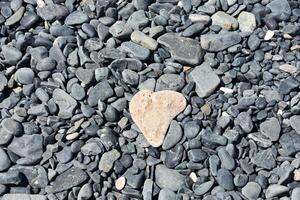 fantastique cœur en forme de pierre sur une foncé pierre plage photo