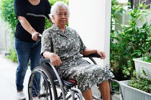 soignant Aidez-moi asiatique personnes âgées femme invalidité patient séance sur fauteuil roulant dans hôpital, médical concept. photo