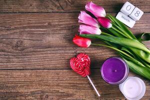 rose tulipe fleurs, sucette, le Date bloquer calendrier et deux cendels sur rustique table pour Mars 8, international aux femmes jour, anniversaire, valentines journée ou les mères journée - Haut vue photo