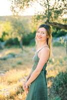 souriant Jeune femme des stands demi-tourné près une arbre photo