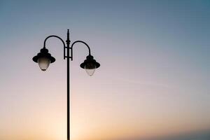 rue double lampe sur le Contexte de une coloré le coucher du soleil photo